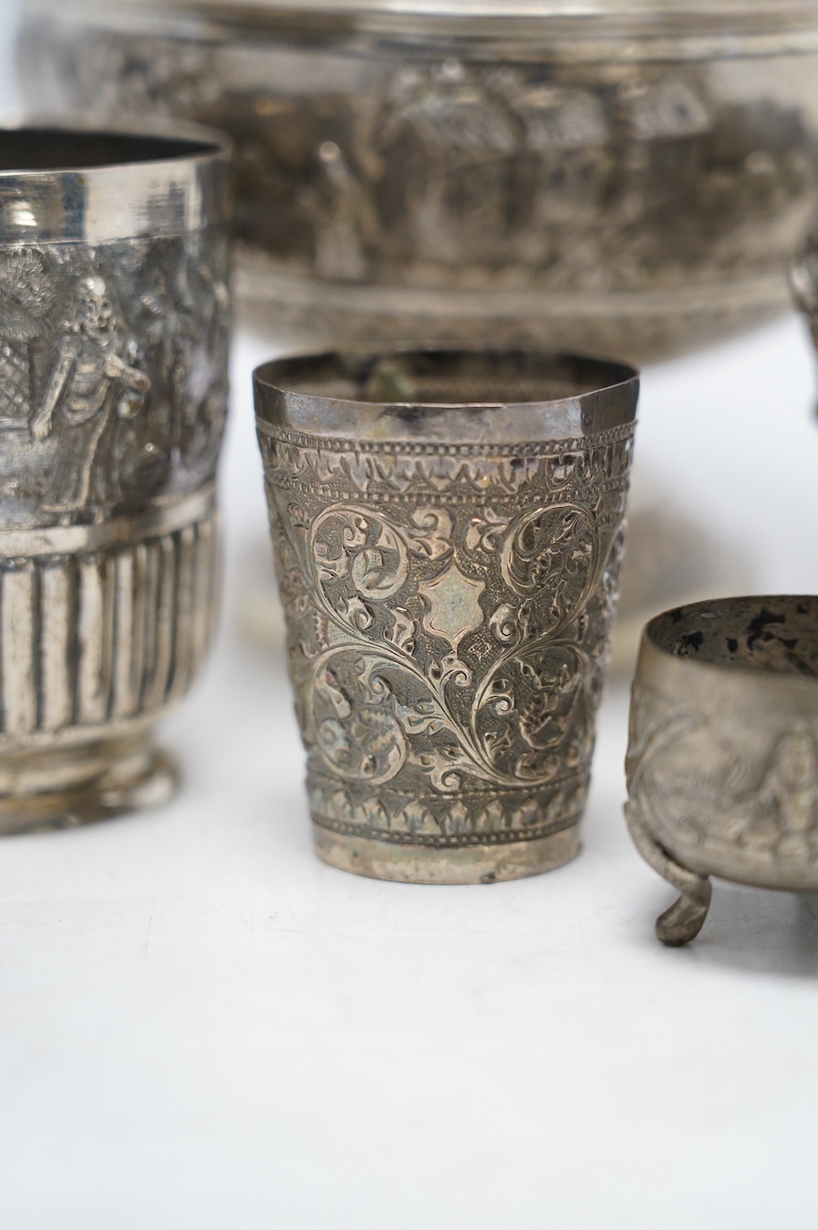 An Indian repousse white metal pedestal bowl, diameter 15.5cm (a.f.), a similar mug, small vase, condiment and small beaker. Condition - poor to fair